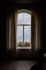 Serene room with large window overlooking lake and cloudy sky