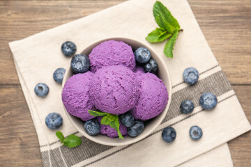 Tasty sorbet with blueberries and mint in bowl on wooden table, top view