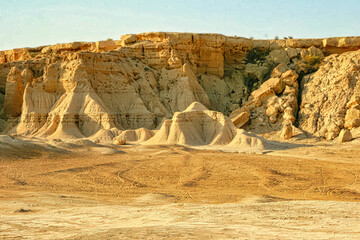 A desert landscape with a large rock formation in the background