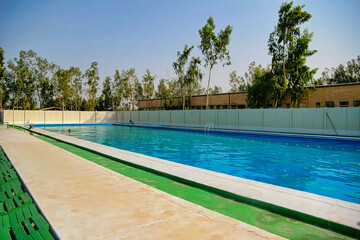 A pool with a green border and a white fence