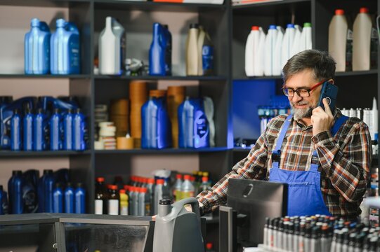 Salesman talking on phone and showing motor oil in auto parts store