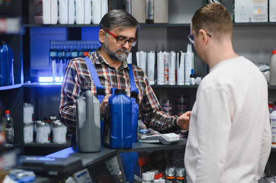 Salesman showing motor oil to customer in auto parts store