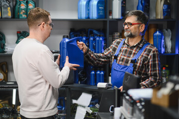 Salesman giving motor oil to customer in auto parts store