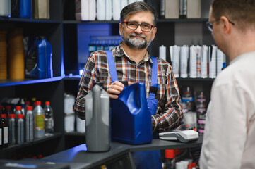 Salesman showing motor oil to customer in auto parts store