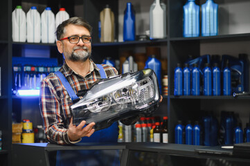 Salesman holding new car headlight in auto parts store