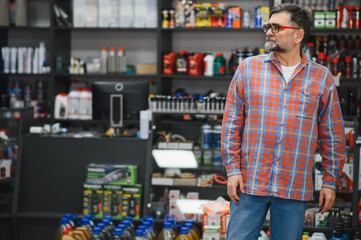 Salesman standing in auto parts store looking at products