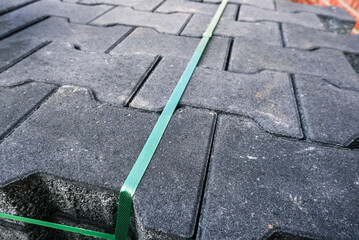 Konzept Baustelle Vorbereitung, Lieferung, Pause oder Baustopp: Unterschiedliche Pflastersteine auf Paletten gestapelt auf einem Grundst&uuml;ck vor einer roten Klinkerwand &ndash; selektiver Fokus, Textfreiraum