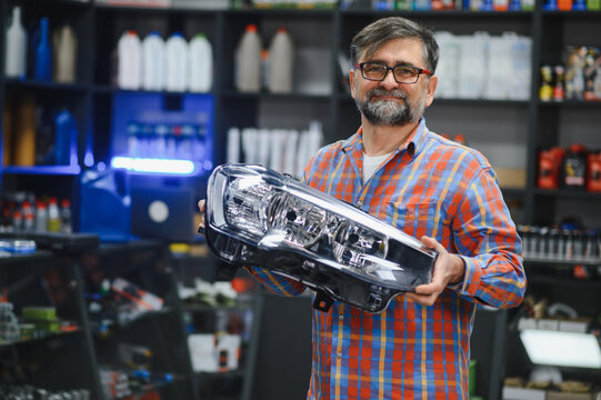 Salesman holding car headlight in auto parts store