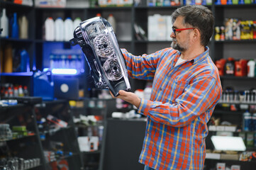 Salesman holding car headlight in auto parts store