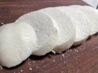 Close up of sliced steamed buns on a wooden board. Soft fluffy Chinese wheat based staple ideal for cooking or snacking.