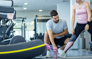 Personal fitness trainer supervising middle aged woman during gym workout.