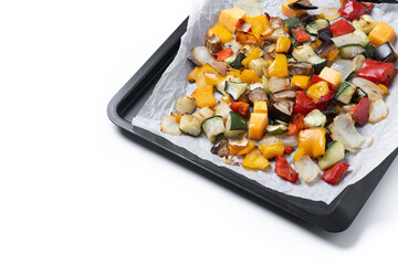 Roasted vegetables on a baking tray isolated on white background. Copy space