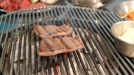 Korean Barbecue Grill Setup with Fresh Beef, Side Dishes, and Vegetables at Traditional Restaurant Table