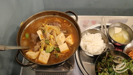 Korean Barbecue Grill Setup with Fresh Beef, Side Dishes, and Vegetables at Traditional Restaurant Table