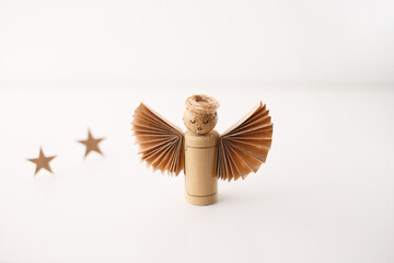 Studio shot of handmade cork angel with drawn face, twine halo, paper wings and stars on white....
