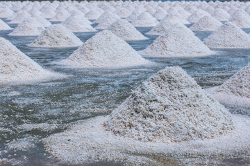 Pyramids of sea salt ready to be harvested in a salt farm at sunrise. Used as a seasoning in food,...
