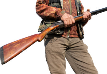 Mature man hunter with gun while walking on field.