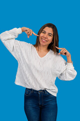 Young latin woman pointing at herself with a blue background