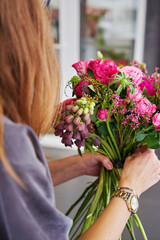 Woman arranging vibrant, fresh flower bouquet with roses