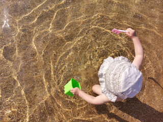 Child playing on beach on sunny summer day, top view