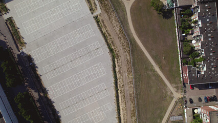 Top down aerial showing landscaping of park with real estate houses next to graphic elements in concrete of neighbouring empty parking lot spaces