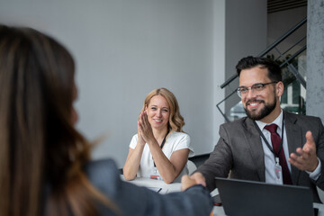Business partners shaking hands at a meeting with their hr manager clapping