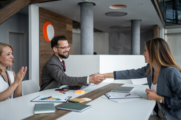 Business people shaking hands after successful meeting in modern office