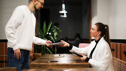 A man and woman meeting in a café to discuss work matters over a laptop