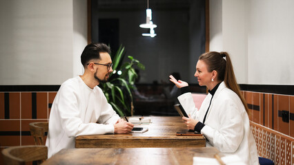 Business partners having a work discussion at a café table with laptop