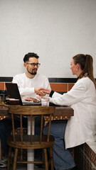 A man and woman meeting in a café to discuss work matters over a laptop