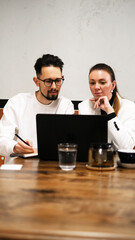 Professional man and woman collaborating over laptops during a café business meeting