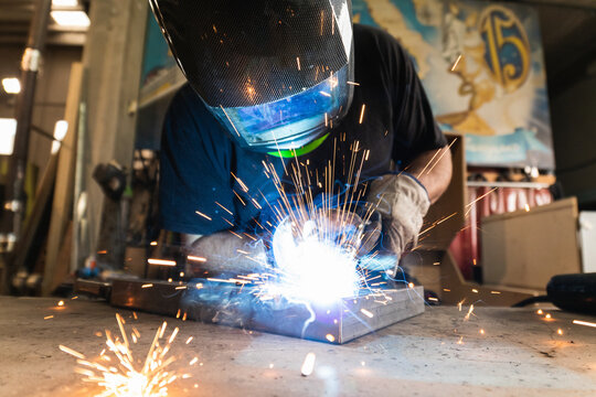 Man is working at metal factory, he is welding a piece of rail using special tools