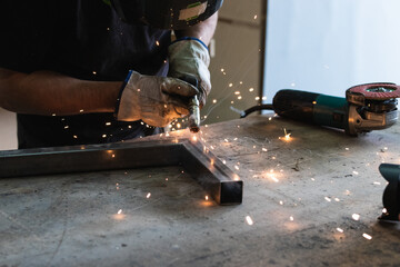 Young man in protective workwear welding in a factory