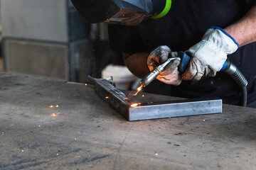 handyman welding and grinding metal at workshop