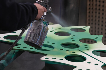 Man painting decorative products with a spray gun