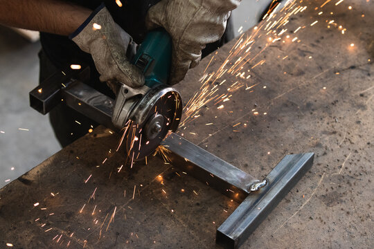 Professional welder welding metal construction parts in industrial workshop. An experienced worker cutting iron parts