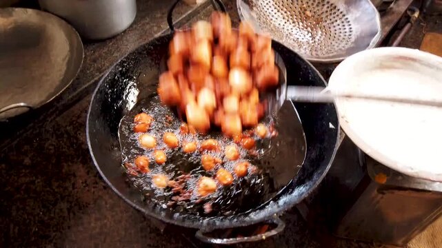 Mysuru, Karnataka, India-April 10 2025; A Kitchen scene where the famous Indian snack 'Aloo tikka' is being prepared by deep frying in a iron pan with cooking oil in India.
