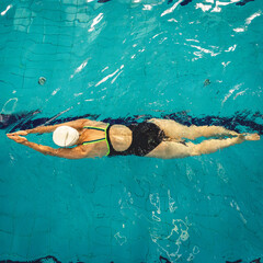 Woman swimming with swimming hat and swimsuit in swimming pool