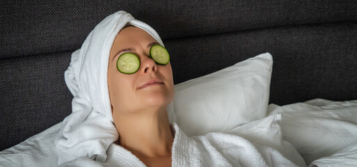 young woman getting eye nature treatment by cucumber at luxury spa resort. Wellness and healing...