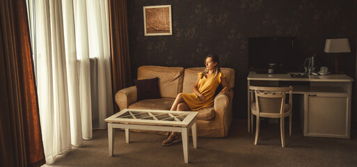 Young woman in yellow dress sitting on sofa