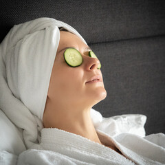 young woman getting eye nature treatment by cucumber at luxury spa resort. Wellness and healing concept.