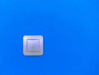 Modern light switch on a vibrant blue wall providing a striking contrast