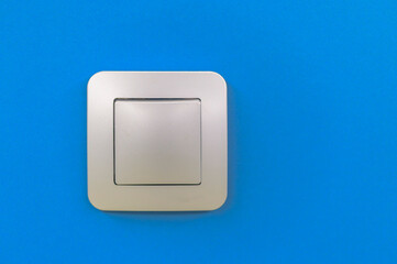 Modern light switch on blue wall representing energy saving