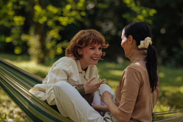 Fototapeta premium Two girls having fun in the park, sitting in a hammock