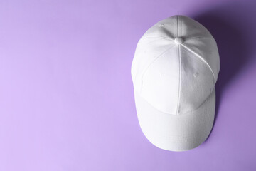 White baseball hat on violet background, top view. Space for text