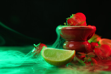 Hookah bowl with limes, strawberries, mint and smoke on black table, closeup. Space for text