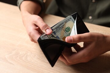 Man counting money at wooden table, closeup