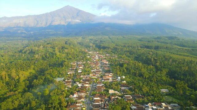 A beautiful village lies peacefully beneath Mount Arjuna, partially obscured by morning clouds.