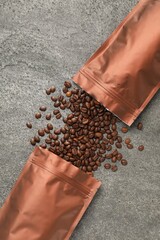 Zipper stand-up pouches and coffee beans on grey table, flat lay. Mockup for design