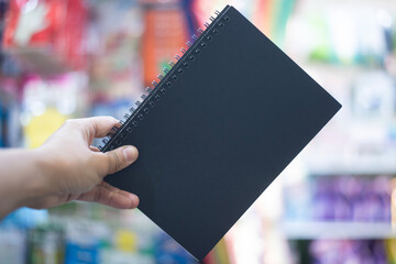 Hand Holding a Blank Black Notebook